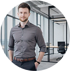 A person with short brown hair standing confidently in a contemporary office space